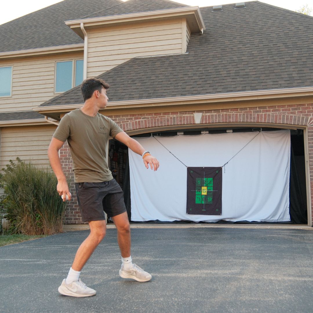 kid throwing baseball into G-TRAK target with garage door up and open.